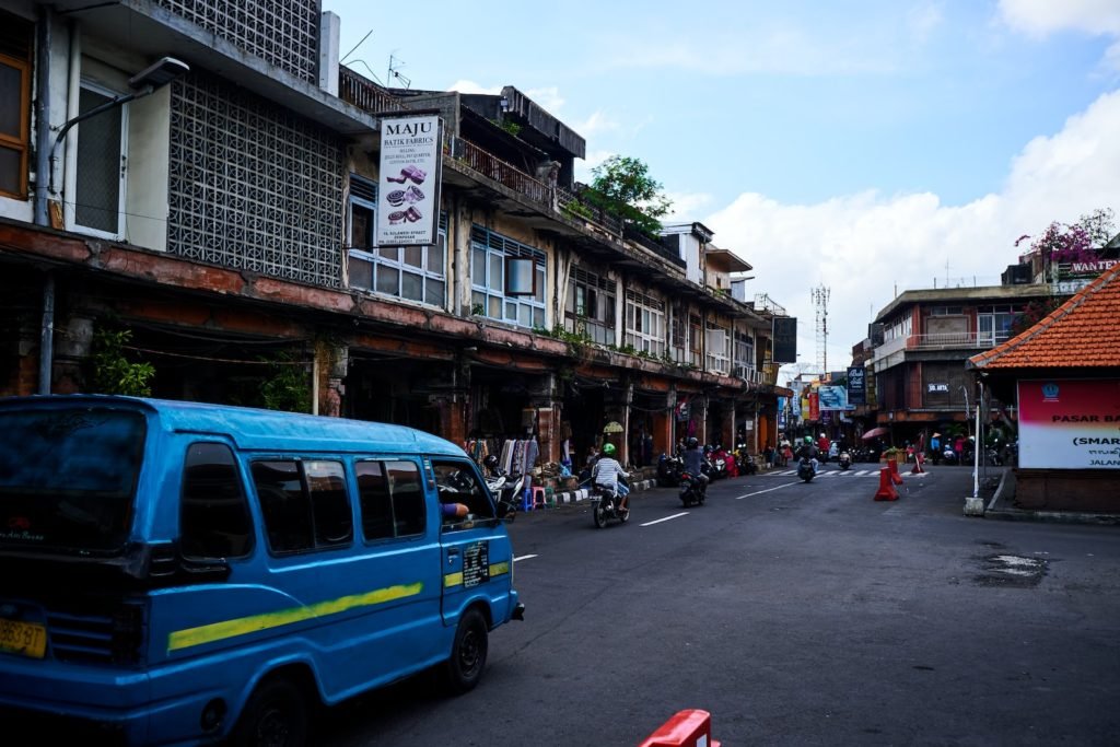 blue van on road near buildings during daytime