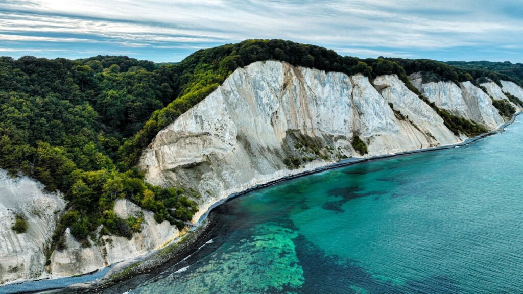 Stunning aerial view of white cliffs against a vibrant turquoise sea and lush greenery.