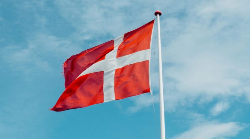 Red and white Danish flag fluttering in the wind, symbolizing national pride on a clear day.